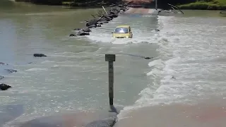Small car takes on notorious river crossing as croc swims past