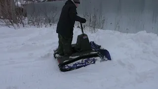 Гусеничный самокат чистит сырой снег.