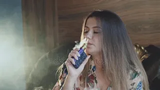 Passionate lady smoking e-cigarette and breathing out through mouth and nose