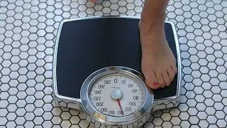 WOMAN STEPPING ONTO A SCALE TO CHECK HER WEIGHT 4K