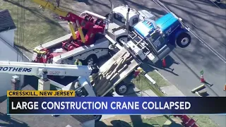 Massive construction crane gets tangled in power wires during collapse