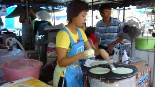 Thai food vendor making green crepes