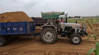 Eicher 333 tractor pulling a loaded trolley in the field