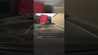Car narrowly escapes being crushed by a truck