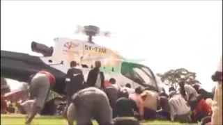 Man holds on to helicopter as it lifts off