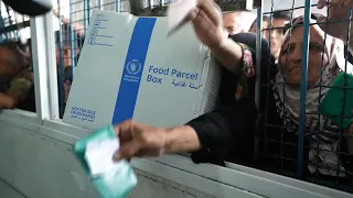 Scores of people queue for boxes of aid in Deir al-Balah