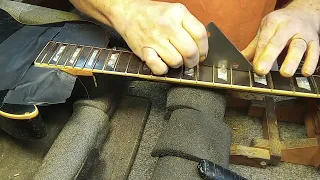 Checking with a rocker to find high spots on the frets.