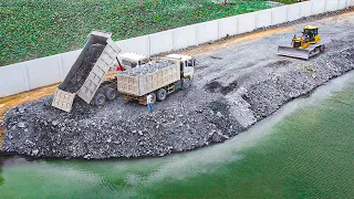 Amazing bulldozer Dozer Pushing Stone Into Water Building New Road Over Big Lake Push Rock And Truck