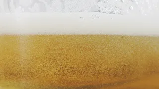 FREE STOCK VIDEO 4K | Detail Shot of Rippling Beer Bubbles and Foam in Glass