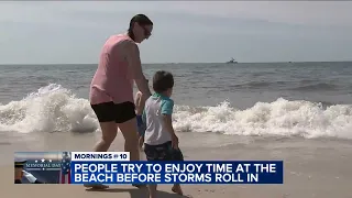 People try to enjoy time at the beach before storms roll in