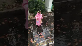 Little girl in a raincoat playing with water；#short