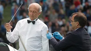 Hungarian conductor promotes vaccination by receiving a jab while performing