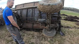 Wesoły kierowca traktora wywraca przyczepę z ziemią kołami do góry