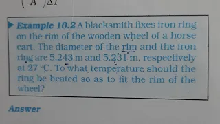 A blacksmith fixes iron ring on the rim of the wooden wheel of a horse cart. The diameter of the rim