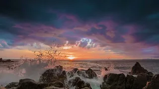 Dramatic sunset on a tropical beach with rocky shoreline in 4K