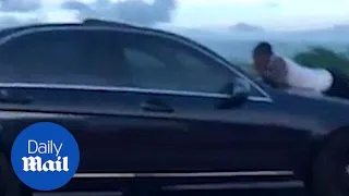 Shocking moment man rides on the hood of a car mid-highway