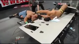 Alberto Del Rio back suplexes John Cena through Announce table