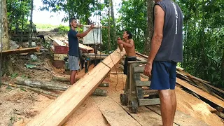 The primitive adventurer splits a large piece of wood on the high cliff using a round saw