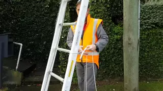 Securing a ladder at the base of a telephone pole