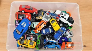 A box full of small and larger cars of various brands