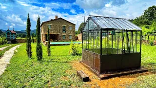 Assembly of a beautiful glass and steel greenhouse. Landscaping and gardening. Timelapse
