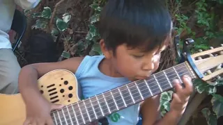 Niño toca en guitarra  el CONDOR PASA. arpegio