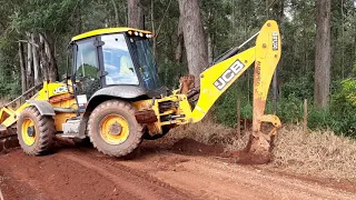 Retroescavadeira abrindo saída d'água por cima da cerca. Backhoe opening water outlet over the fence