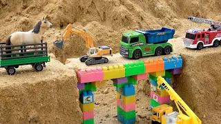 Truk konstruksi menyekop pasir dan membangun mainan jembatan