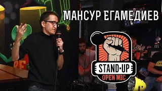 Стендап комик Мансур Егамедиев выступает на открытом микрофоне.