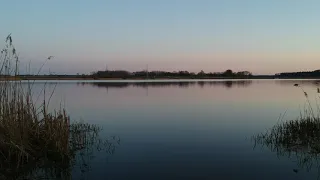 Съемка с дрона над водой. Полет на квадрокоптере низко над водой. Вечернее озеро.