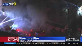 Several fire engines rain water down onto a blaze inside a downtown LA building