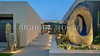 The design of the living room frames a desert view of mountains, trees and sky