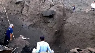 LOWERING SAND OVER THE TOP OF THE CLIFF AND TRYING TO BREAK LARGE ROCKS