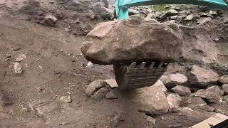 Excavators work to tear down sand cliffs and large rocks in a sand mine