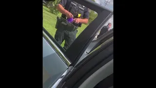 A Caledonia police officer appears to toss an object into a vehicle.