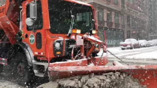 3 DSNY PLOWS & A SALT SPREADER MAKING A PASS ON AMSTERDAM AVENUE DURING WINTER SNOW NIKO IN NYC.
