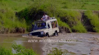 Toyota Land Cruiser drives through deep muddy river waters in Kenya, its bonnet almost submerged