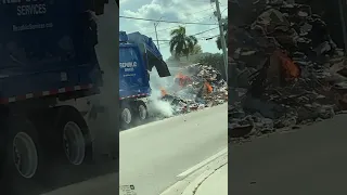 Garbage truck has to dump the whole load of trash on the street because it's on fire!