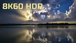 Backlit clouds at sunset with calm water reflections and ambient music. 8K 60fps HDR.