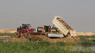 Extreme Bulldozer , wheel loader pushing rock and Dump Truck unloading rock to fill up lake