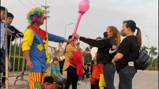 The clown makes balloons at the gate of the industrial park.