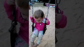 Little baby Alice playing on the swing at the local park