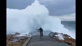 Cyclist has epic wipeout when gigantic wave crashes into pier (Video)